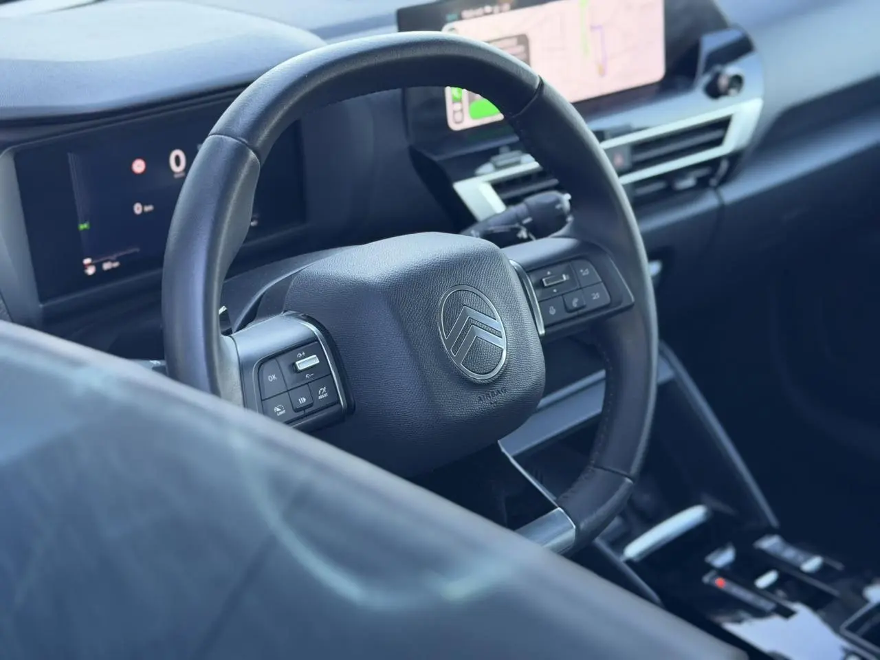 Vue intérieure rapprochée du volant cuir noir et du tableau de bord numérique de la Citroën C4 Hybrid 2025.