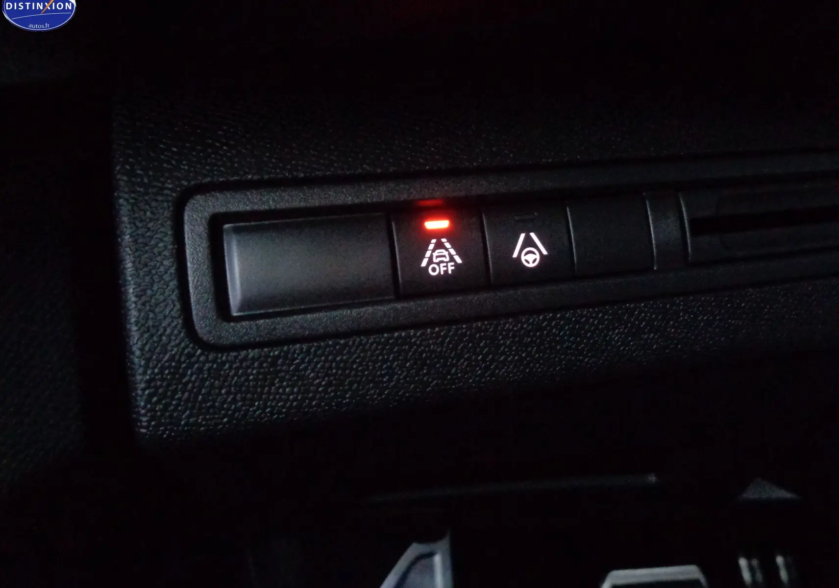 Gros plan sur les boutons de contrôle d'assistance à la conduite du Peugeot 3008 gris platinium, avec témoin d'alerte allumé.