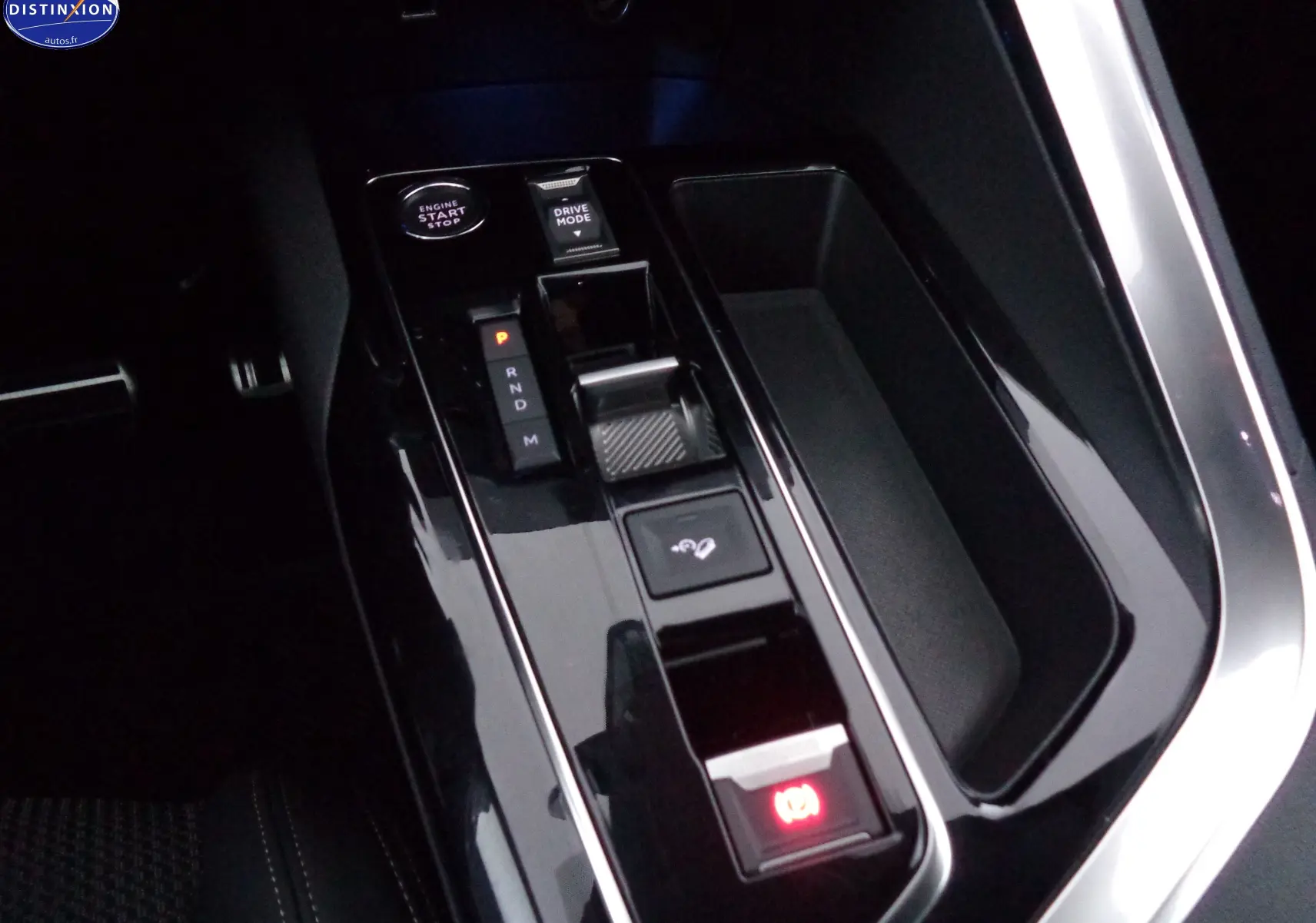 Gros plan sur la console centrale noire brillante du Peugeot 3008 2023 avec levier de boîte auto et bouton start-stop.