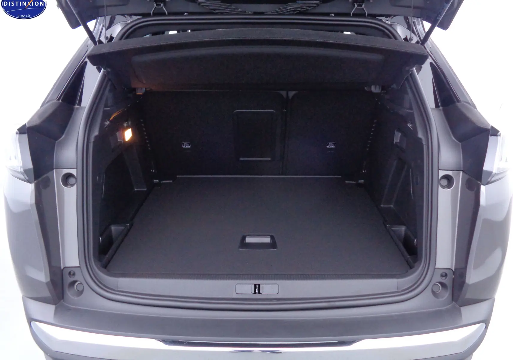 Coffre ouvert du Peugeot 3008 gris platinium métal, vue arrière montrant un espace de chargement spacieux et bien fini.