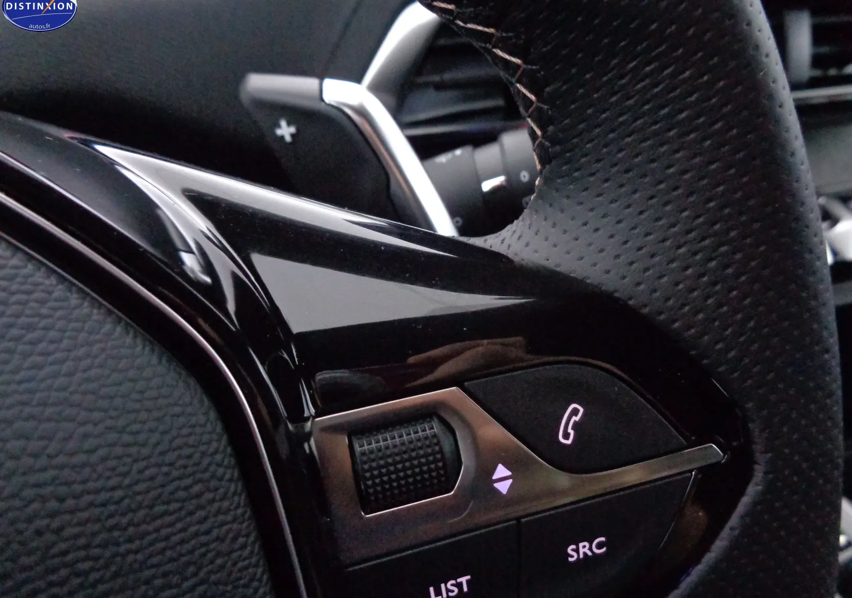 Gros plan sur les commandes du volant en cuir noir du Peugeot 3008 gris platinium 2023, avec molette et bouton téléphone.