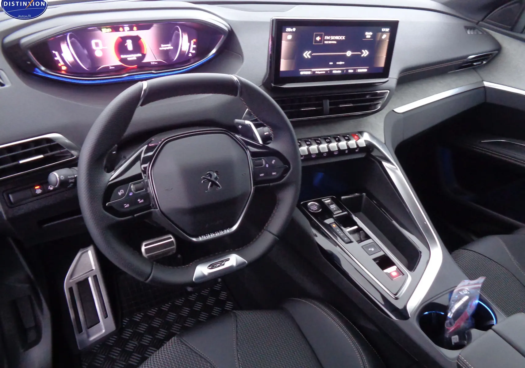Intérieur Peugeot 3008 GT 2023 vu côté conducteur, volant compact, tableau de bord numérique et console centrale moderne noire.
