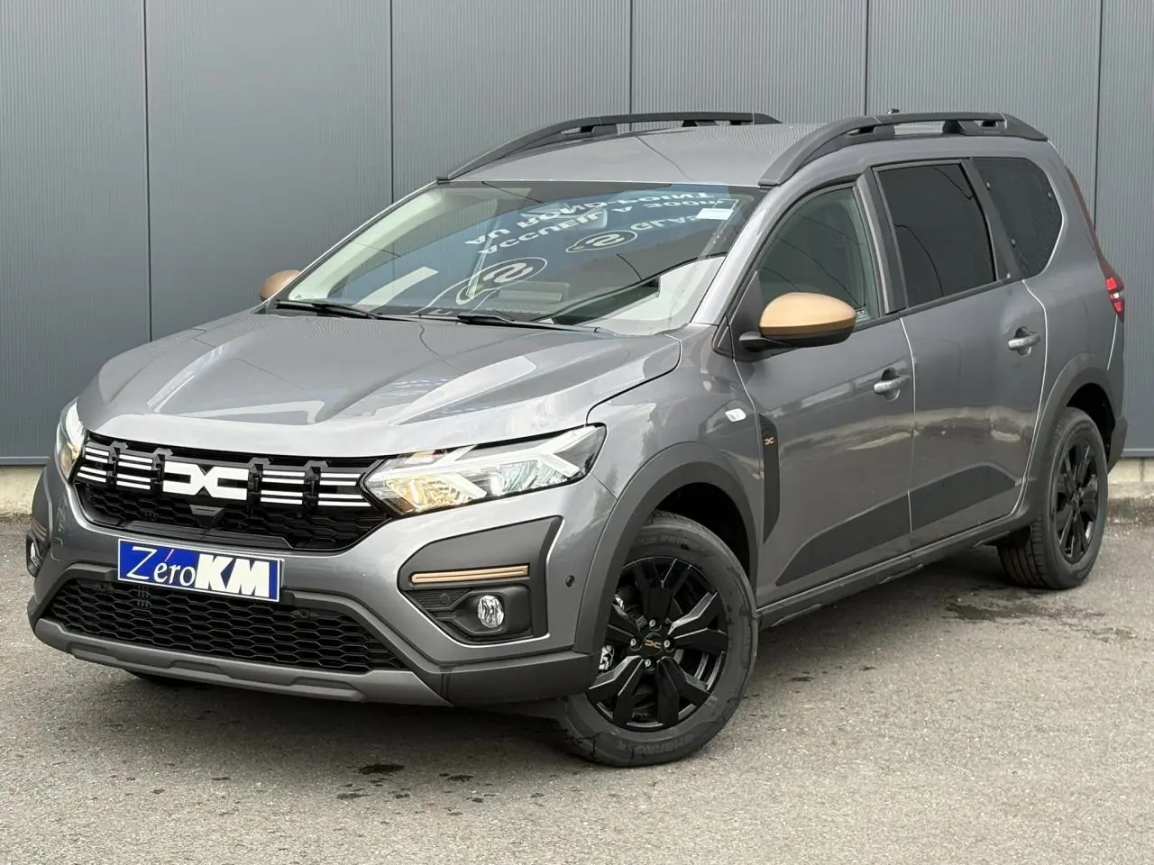 Vue 3/4 avant droit du Dacia Jogger Gris Schiste avec jantes noires et rétroviseurs couleur cuivre.