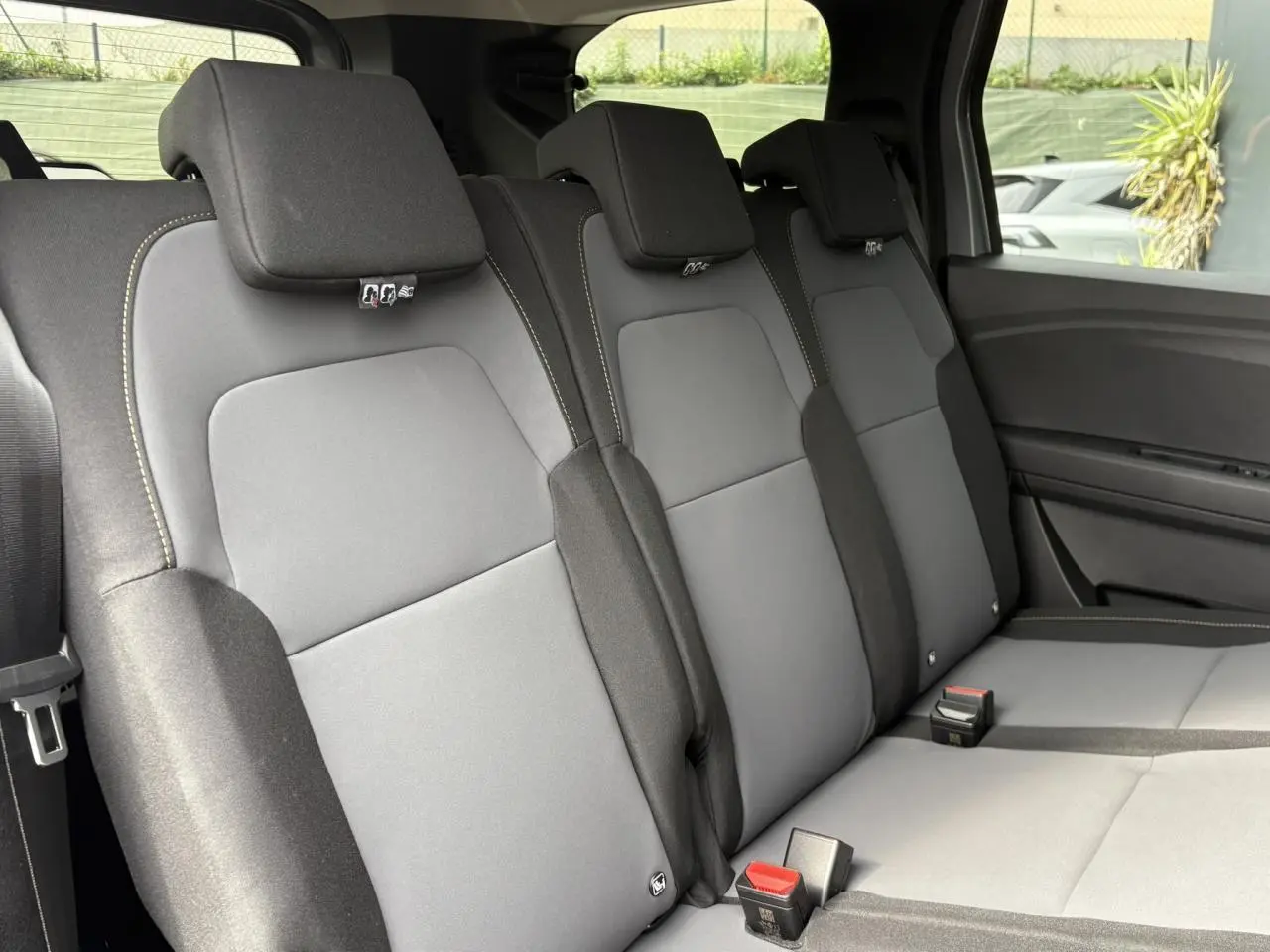 Vue intérieure sur la banquette arrière grise du Dacia Jogger 2025, avec appuie-têtes et ceintures visibles côté droit.