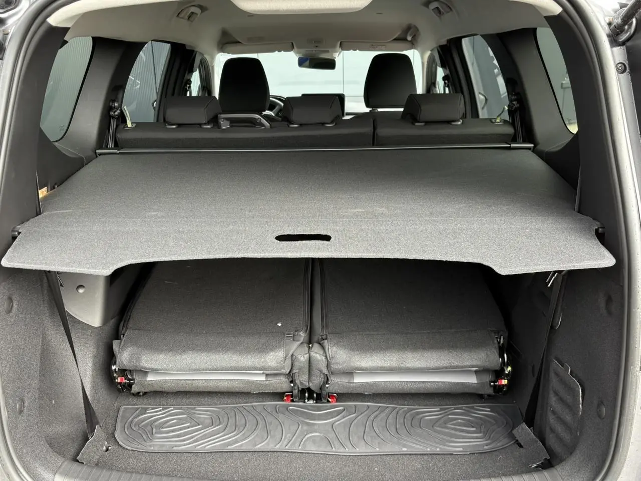 Coffre ouvert vu de l'arrière du Dacia Jogger gris Schiste avec sièges rabattus et cache-bagages déployé.