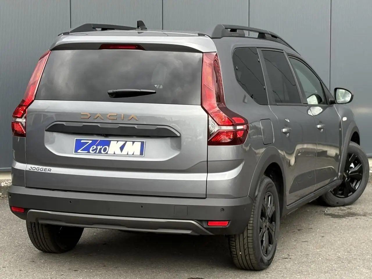 Vue 3/4 arrière droite du Dacia Jogger gris schiste avec vitres arrière surteintées et jantes noires.