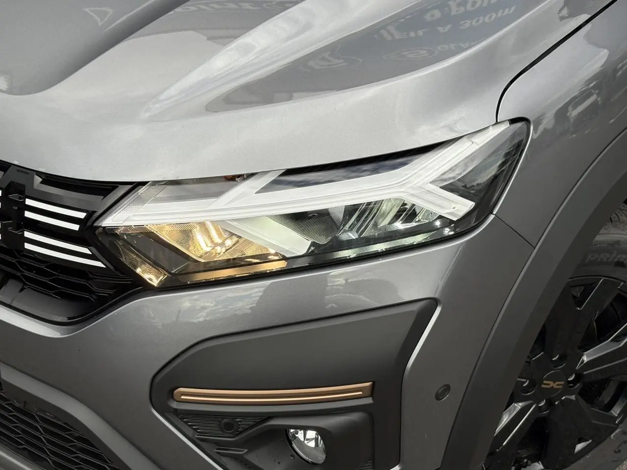 Gros plan sur l'avant droit gris schiste du Dacia Jogger 2025, mettant en valeur le phare LED et la jante noire.