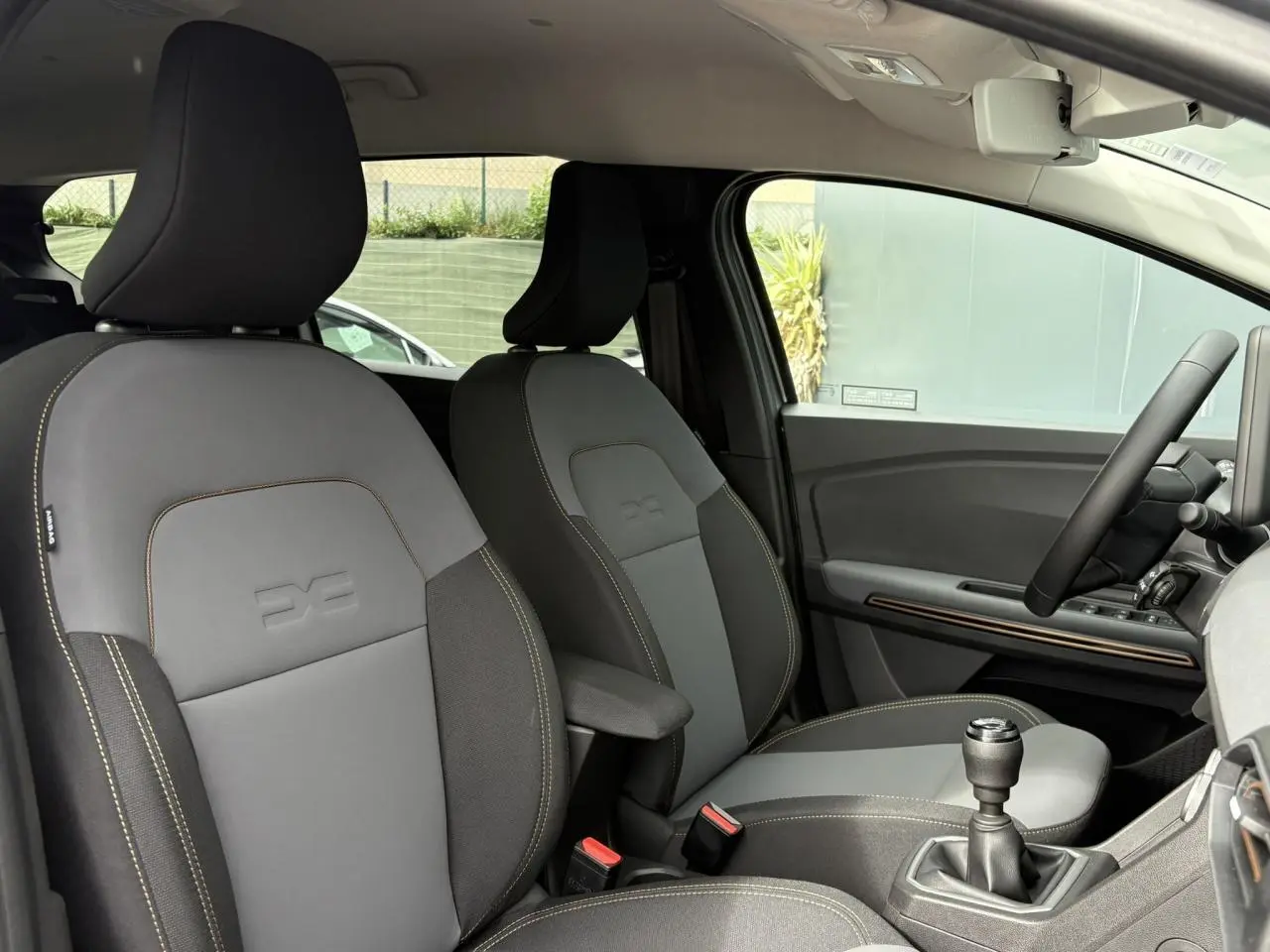 Intérieur avant du Dacia Jogger gris Schiste, sièges mixte TEP Micro Cloud avec surpiqûres brun cuivré et levier de vitesses manuel visible.