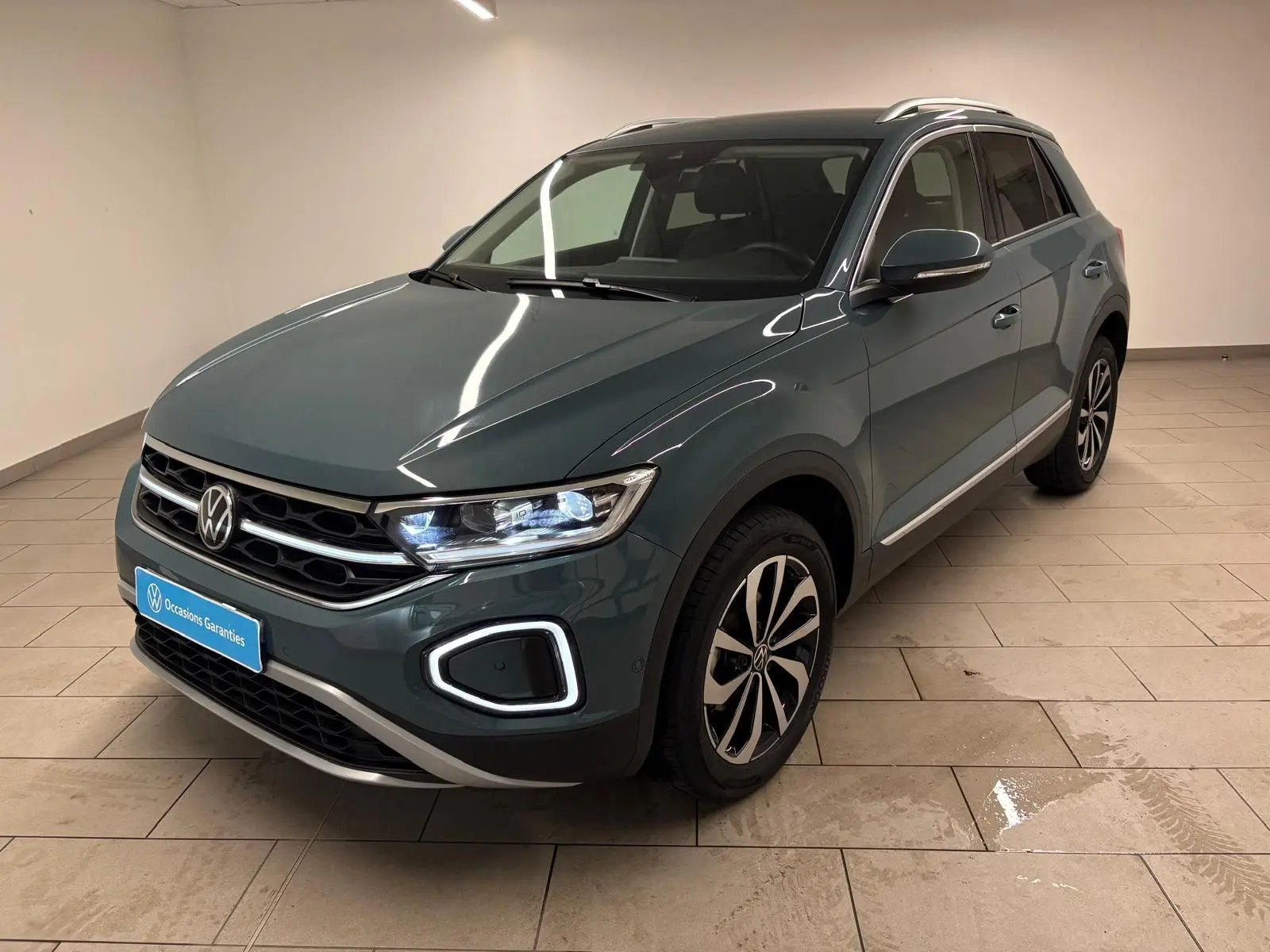 Volkswagen T-Roc bleu pétrole en 3/4 avant droit, avec signature lumineuse LED distinctive et jantes alliage.