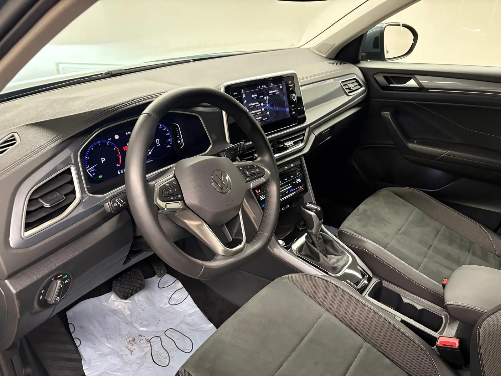 Vue intérieure côté conducteur du Volkswagen T-Roc 2025, volant multifonction, tableau de bord digital et sellerie noire.