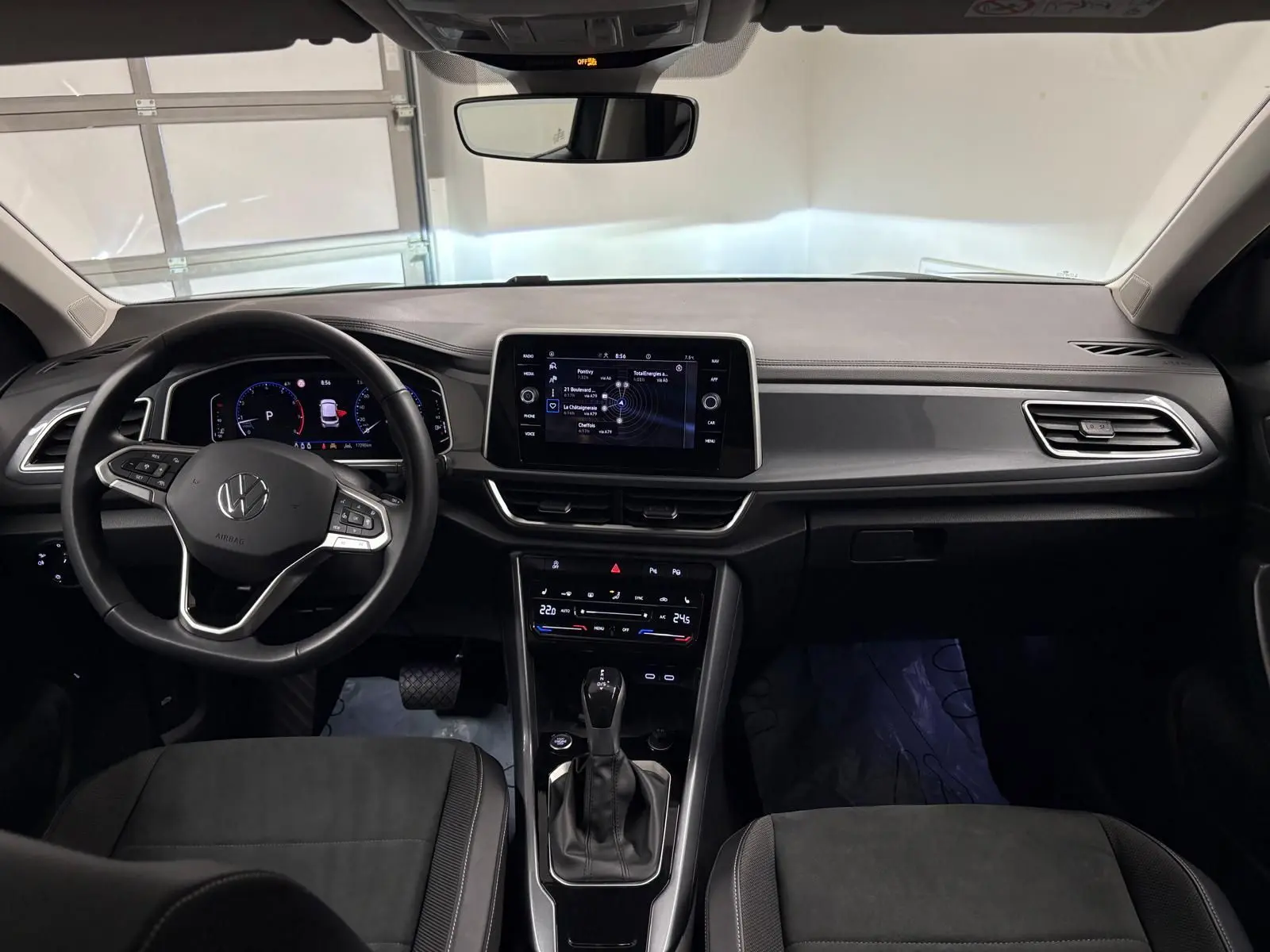Vue intérieure avant du Volkswagen T-Roc 1.5 TSI 2025, tableau de bord noir avec écran tactile central et volant multifonction.