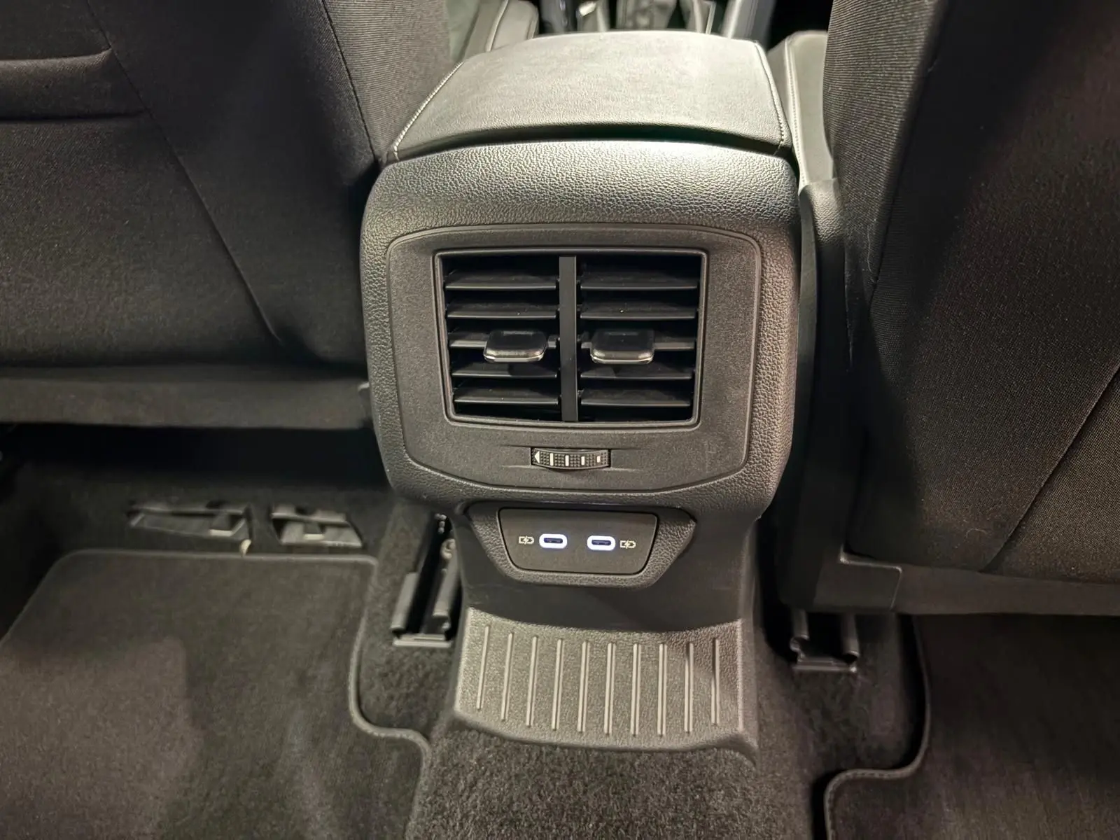 Vue rapprochée de la console arrière du Volkswagen T-Roc 2025, avec sorties d'air et ports USB éclairés.