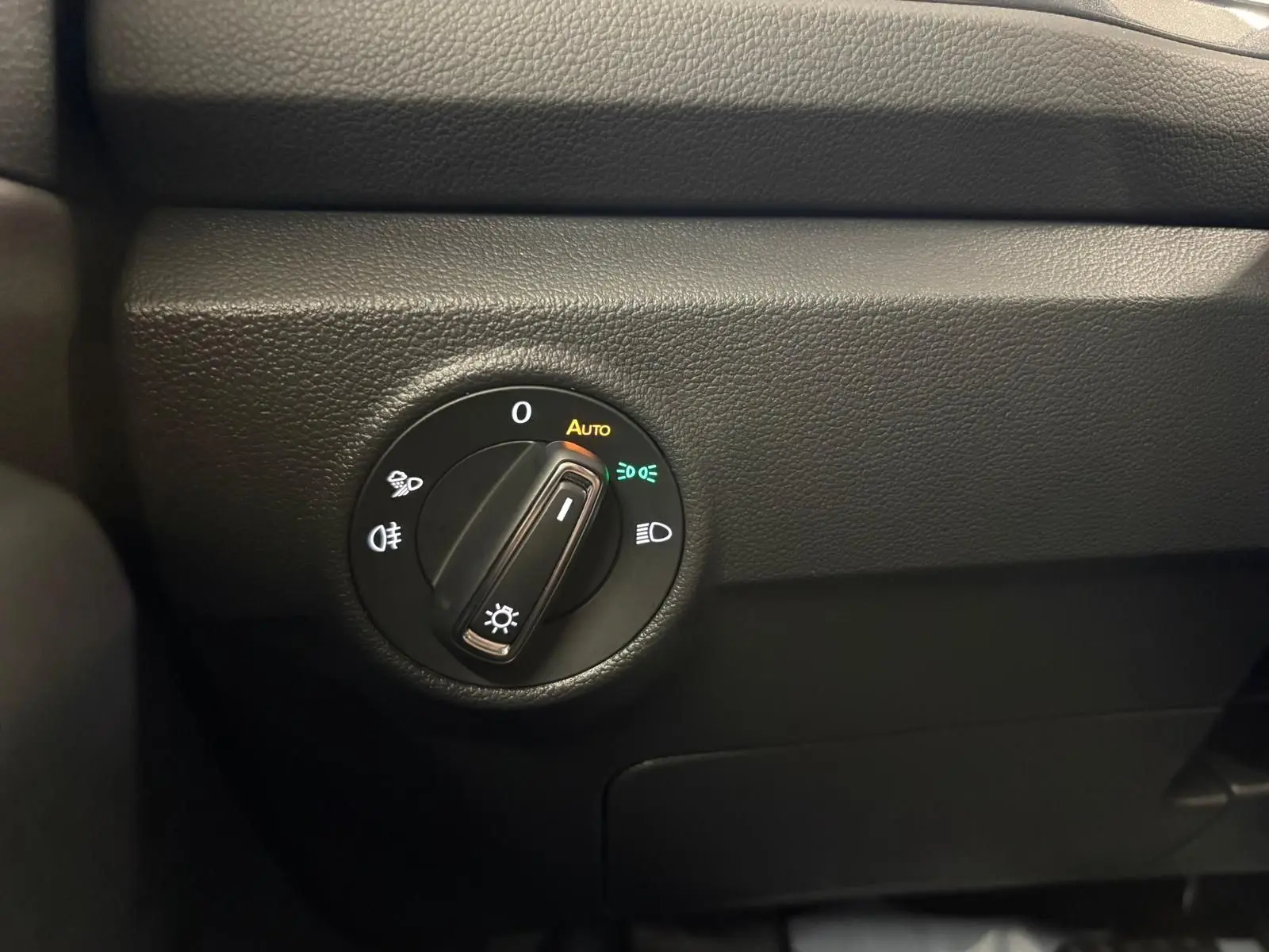 Gros plan sur le bouton de commande des phares du Volkswagen T-Roc 1.5 TSI bleu pétrole, intérieur noir.