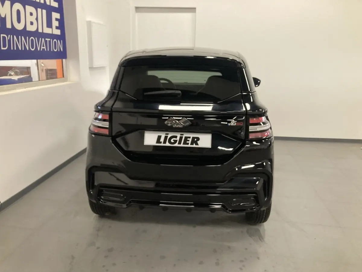 Vue arrière d'une Ligier JS50 noire 2026 avec feux LED et jantes alu noires dans un intérieur blanc.