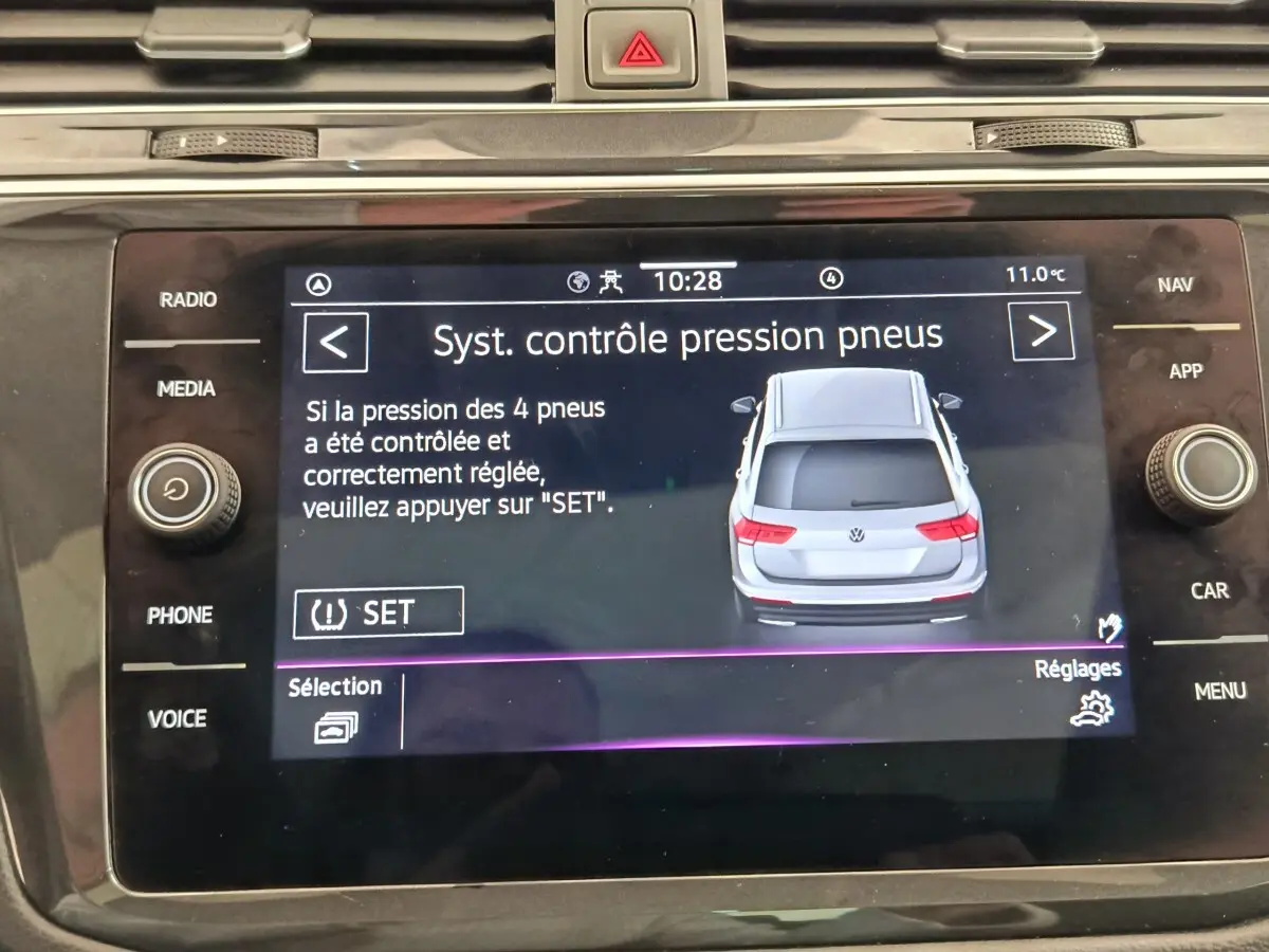 Écran tactile central affichant le contrôle pression pneus avec illustration arrière d'un Volkswagen Tiguan gris clair.