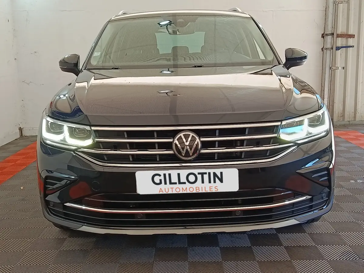 Volkswagen Tiguan noir vue de face avec phares LED allumés et calandre chromée dans un garage.