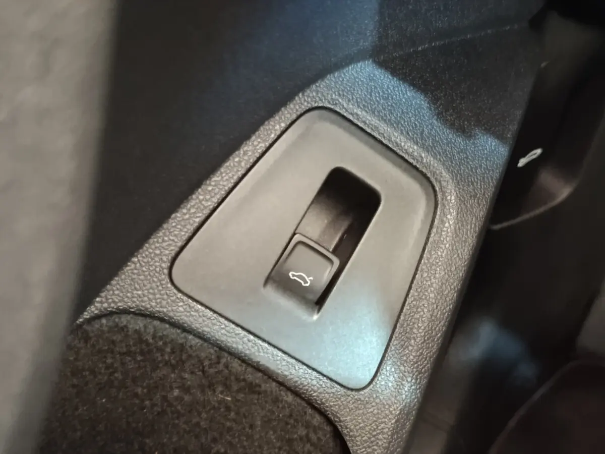 Gros plan sur le bouton d'ouverture électrique du coffre dans l'habitacle du Volkswagen Tiguan noir.
