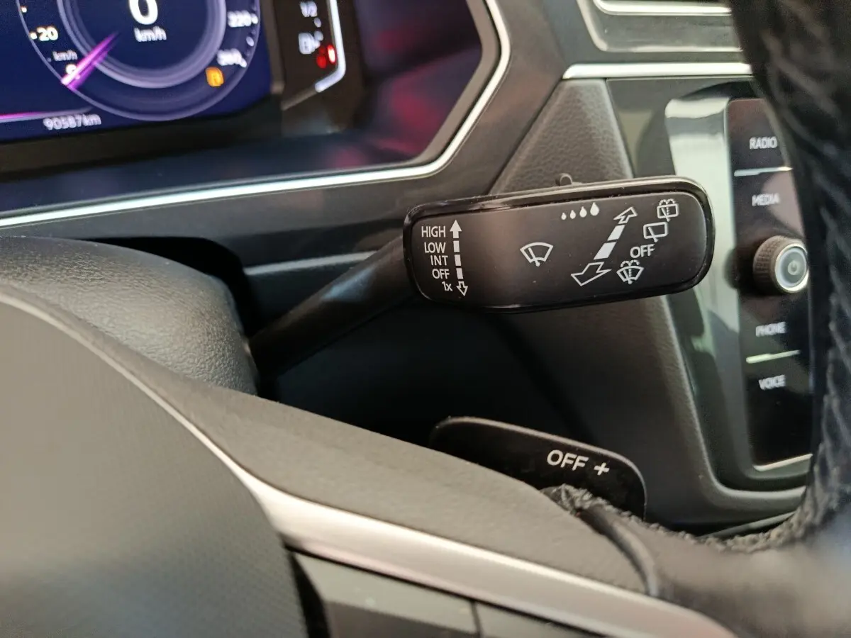 Gros plan sur la manette d'essuie-glace noire à gauche du volant dans l'habitacle du Volkswagen Tiguan 2022.