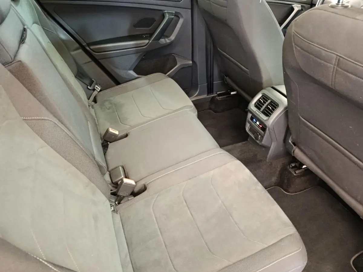 Vue intérieure arrière du Volkswagen Tiguan 2.0 TDI 150 DSG7 Elegance, sièges tissu gris et console centrale avec aérateurs.