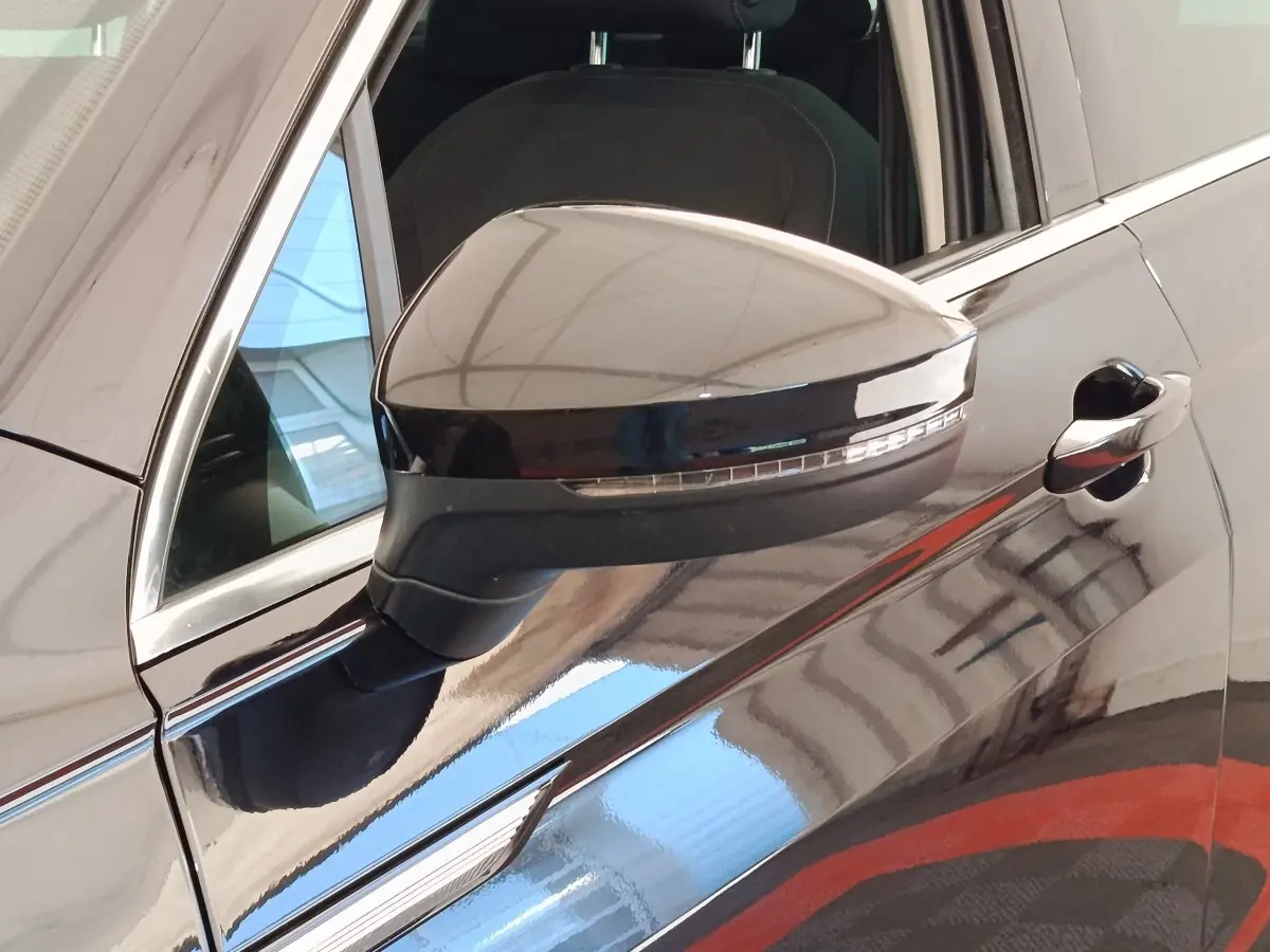 Rétroviseur côté gauche noir brillant du Volkswagen Tiguan 2.0 TDI 150 DSG7 Elegance 2022, avec porte et vitre partiellement visibles.