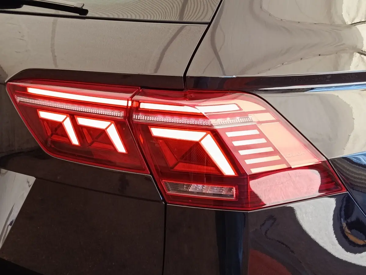 Gros plan sur le feu arrière droit allumé d’un Volkswagen Tiguan noir, soulignant les lignes LED distinctives.