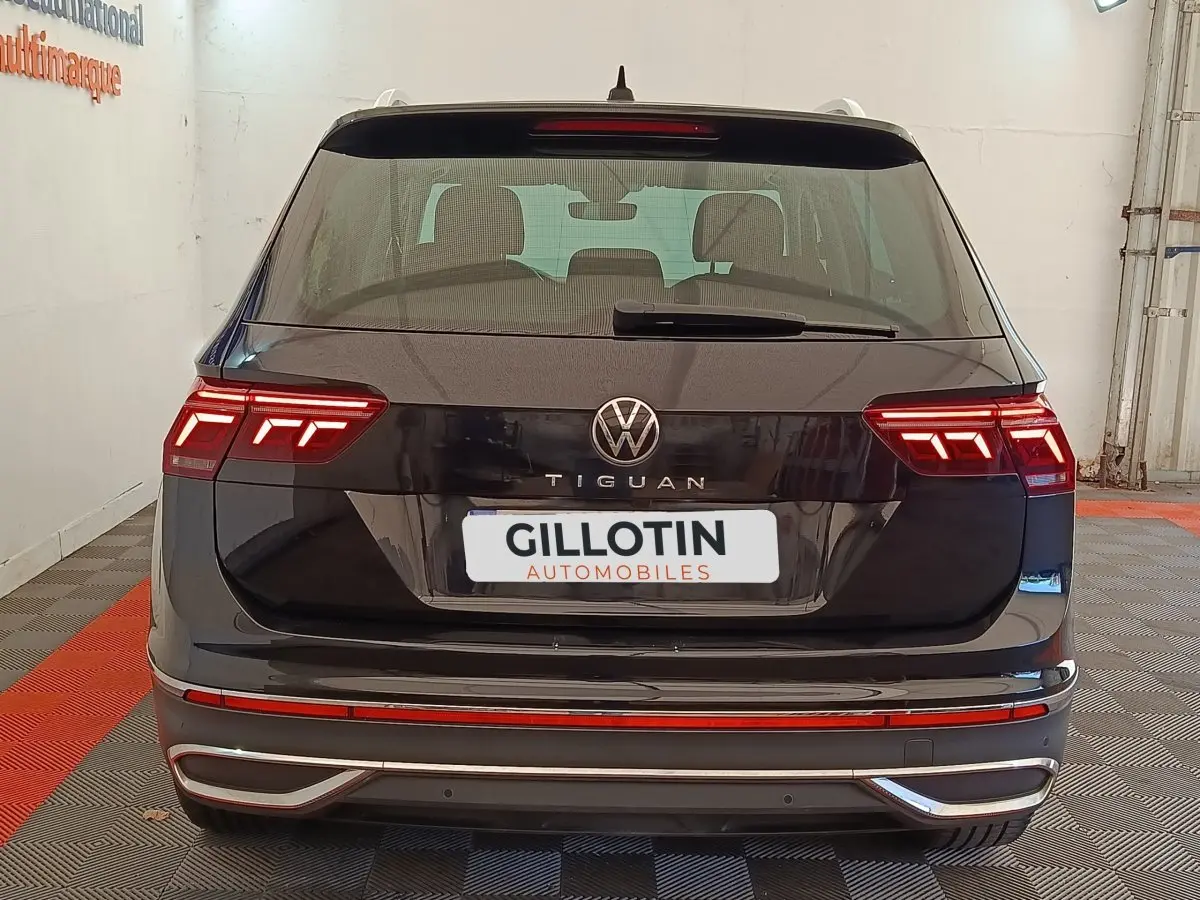 Vue arrière d'un Volkswagen Tiguan noir 2022 avec feux LED allumés dans un garage.
