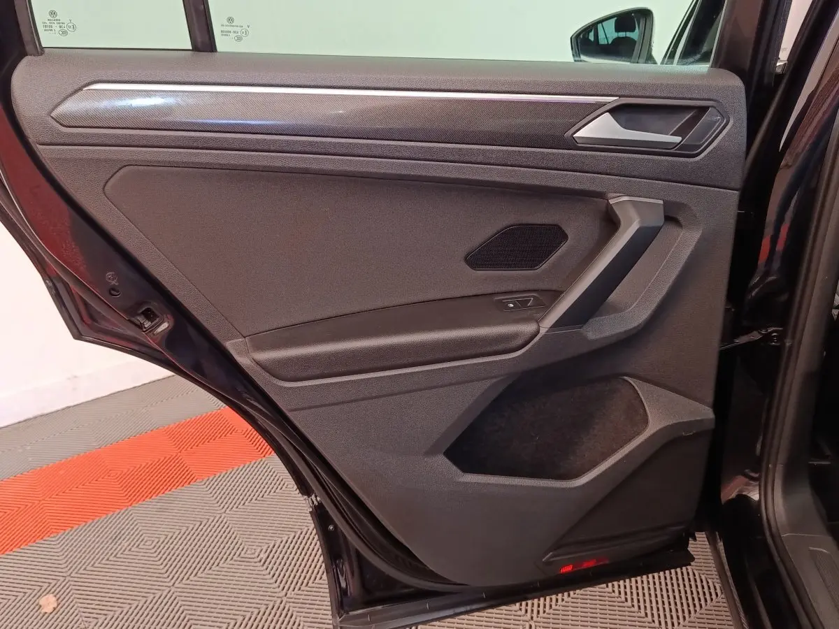 Vue intérieure de la porte arrière gauche noire du Volkswagen Tiguan 2.0 TDI 150 DSG7 Elegance avec habillage sobre.