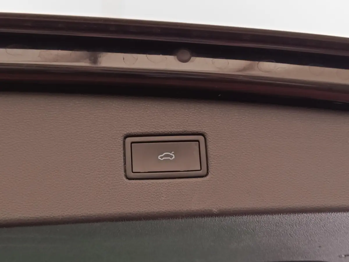Bouton d'ouverture électrique du coffre sur la garniture intérieure d'un Volkswagen Tiguan noir.