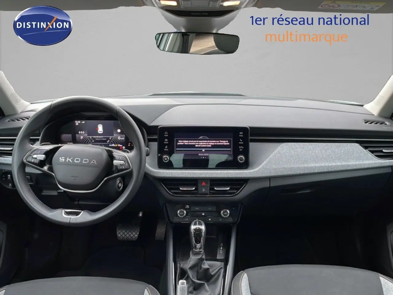 Vue intérieure frontale du Skoda Kamiq 2025 avec tableau de bord gris clair, volant multifonction et écran central tactile.