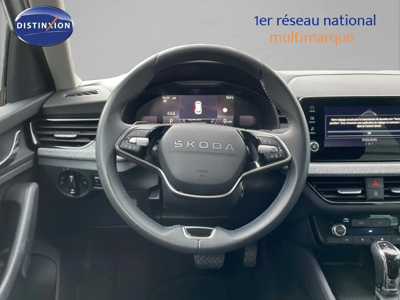 Vue intérieure centrée sur le volant SKODA d’un KAMIQ blanc glacier 2025 avec tableau de bord numérique et écran tactile.