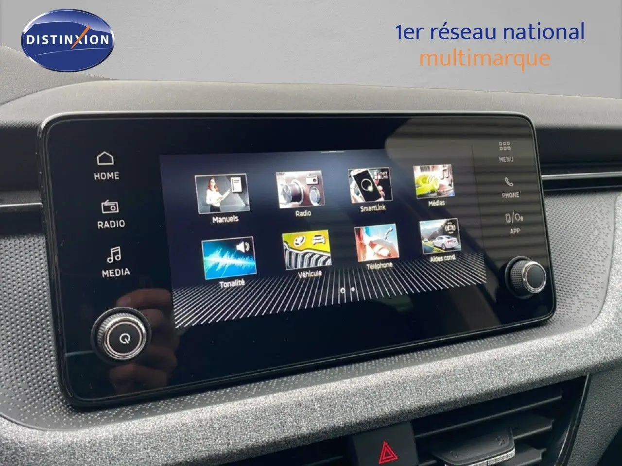 Écran tactile central du Skoda Kamiq blanc glacier, affichant le menu principal avec icônes colorées, vue intérieure rapprochée.