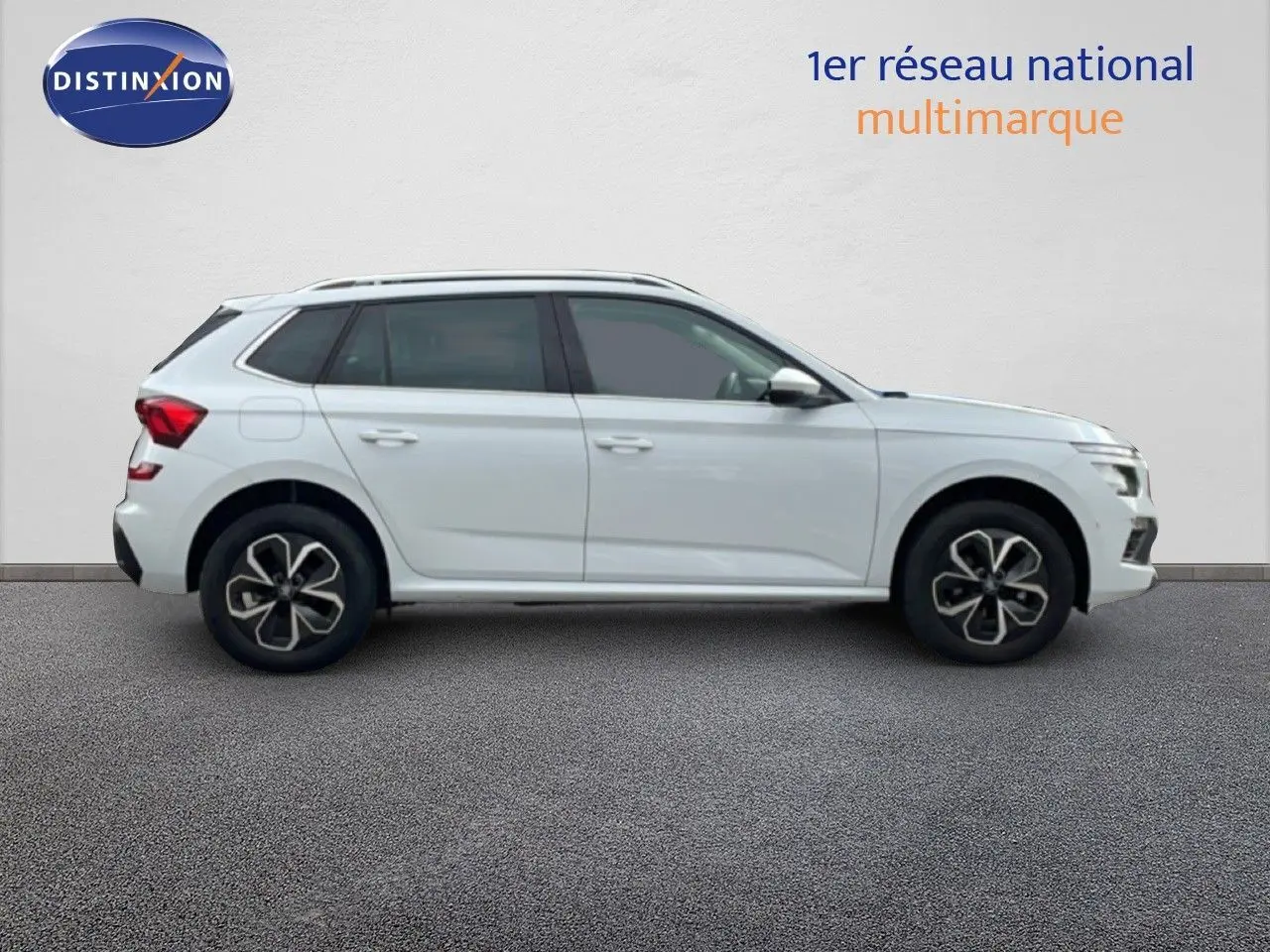 Profil droit d'un Skoda Kamiq blanc glacier 2025 avec jantes alliage et vitres teintées, sur fond neutre intérieur.