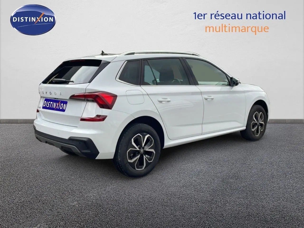 Vue 3/4 arrière droite d’un Skoda Kamiq blanc glacier avec jantes noires et toit ouvrant visible.