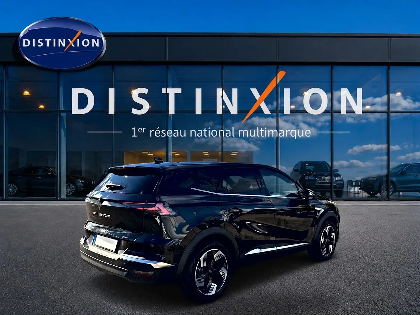 Vue 3/4 arrière droite d'un Renault Symbioz noir étoile avec jantes alu et feux arrière LED devant un showroom Distinxion.