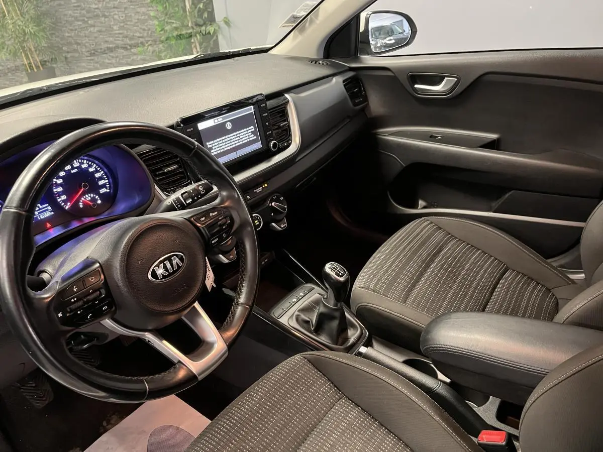 Vue intérieure côté conducteur du Kia Stonic 2019, volant cuir, console centrale avec écran tactile et levier de vitesse manuel.