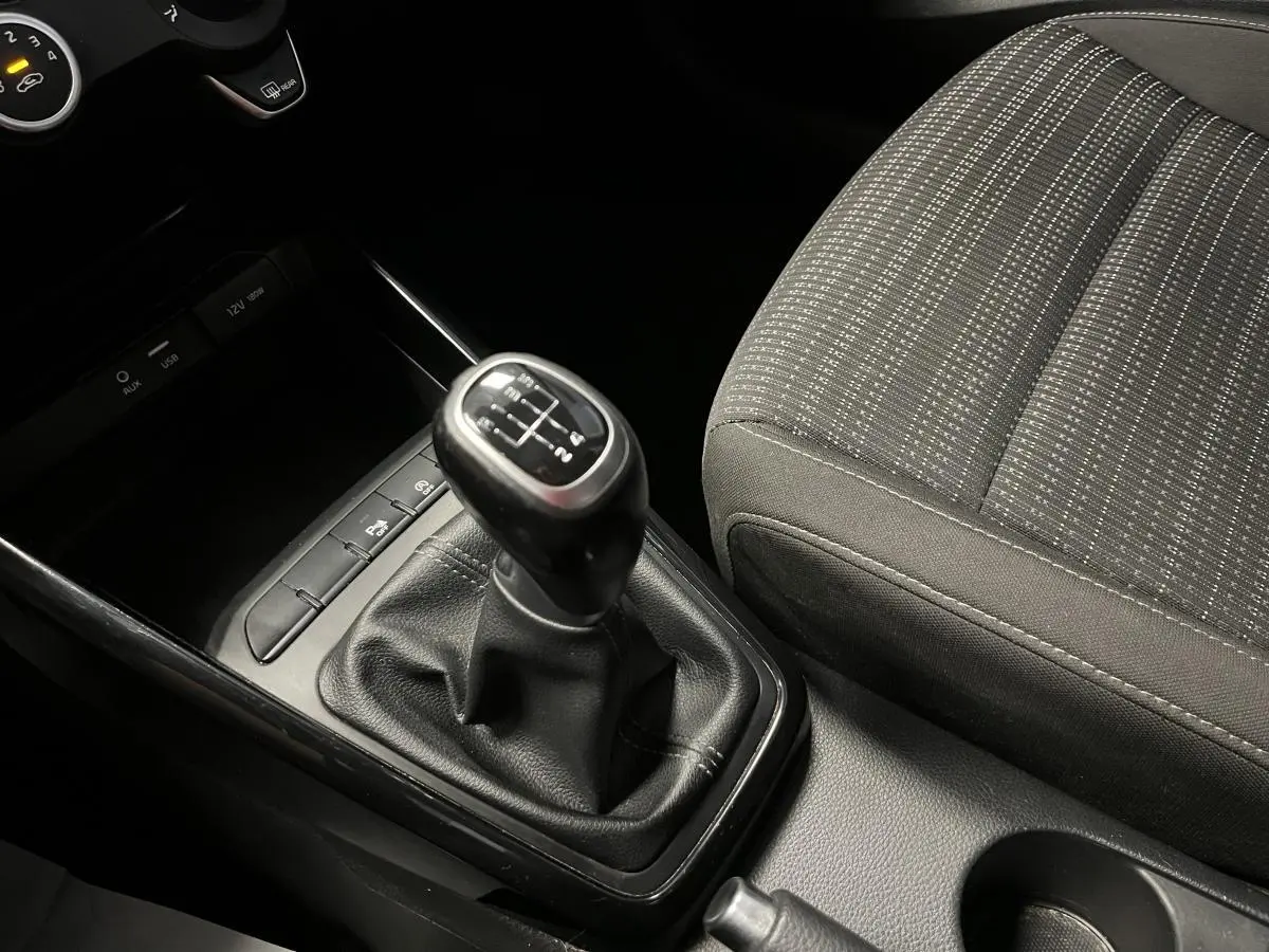 Le levier de vitesses manuel noir et la console centrale avec porte-gobelets du Kia Stonic 2019 en tissu noir.
