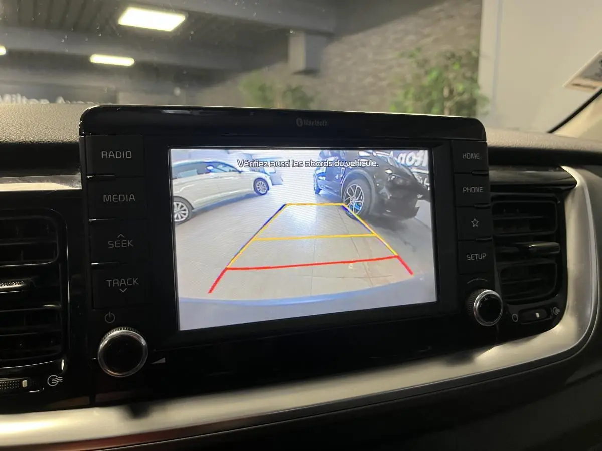 Écran tactile 7'' de la Kia Stonic blanc montrant la caméra de recul avec lignes de guidage actives.
