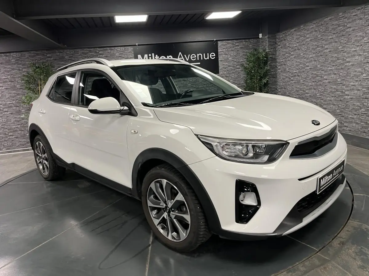 KIA Stonic blanc vue 3/4 avant droit avec jantes alliage et calandre noir laqué en intérieur showroom.