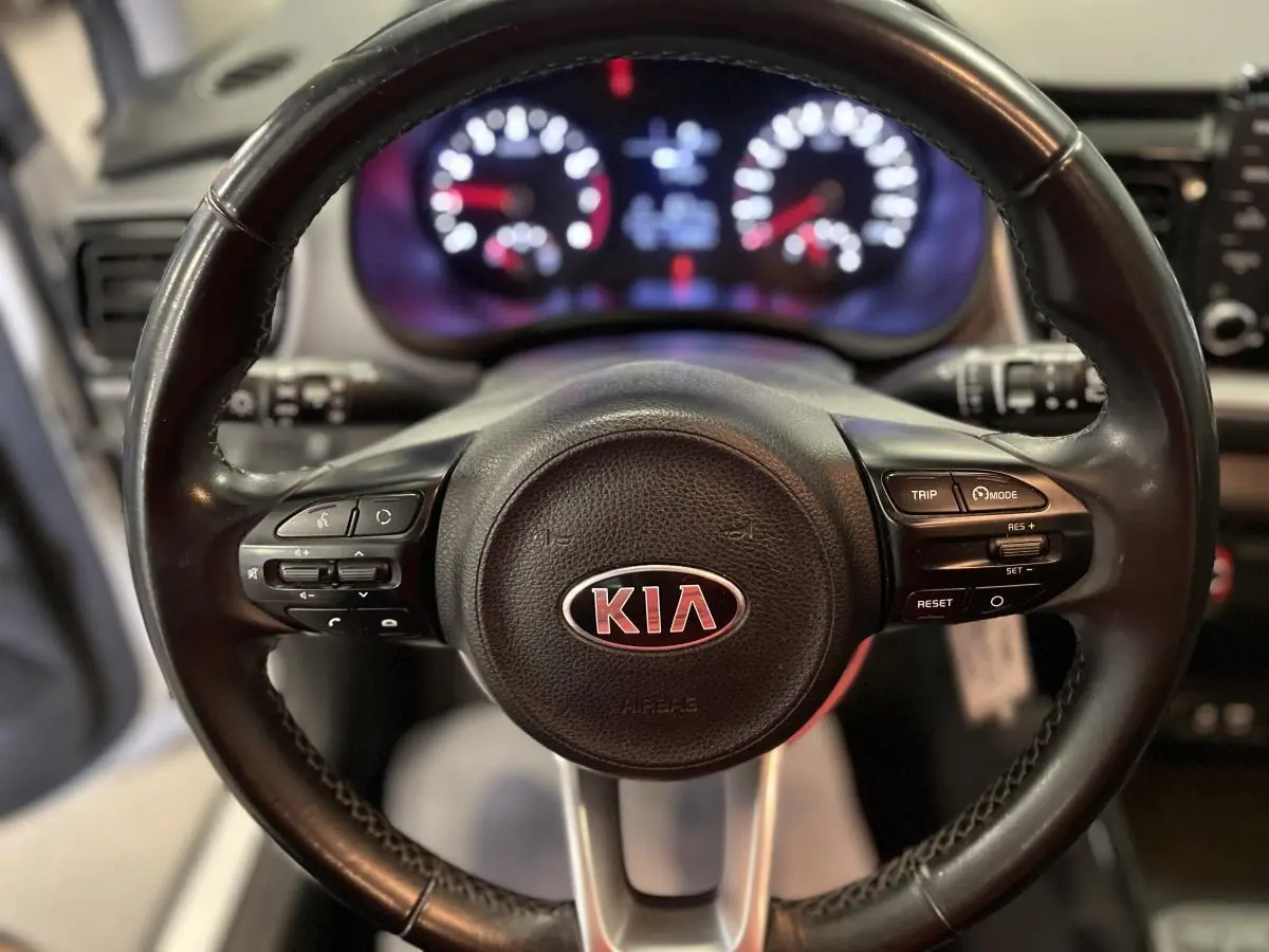 Gros plan sur le volant cuir noir du Kia Stonic 2019 avec commandes intégrées et logo central rouge.