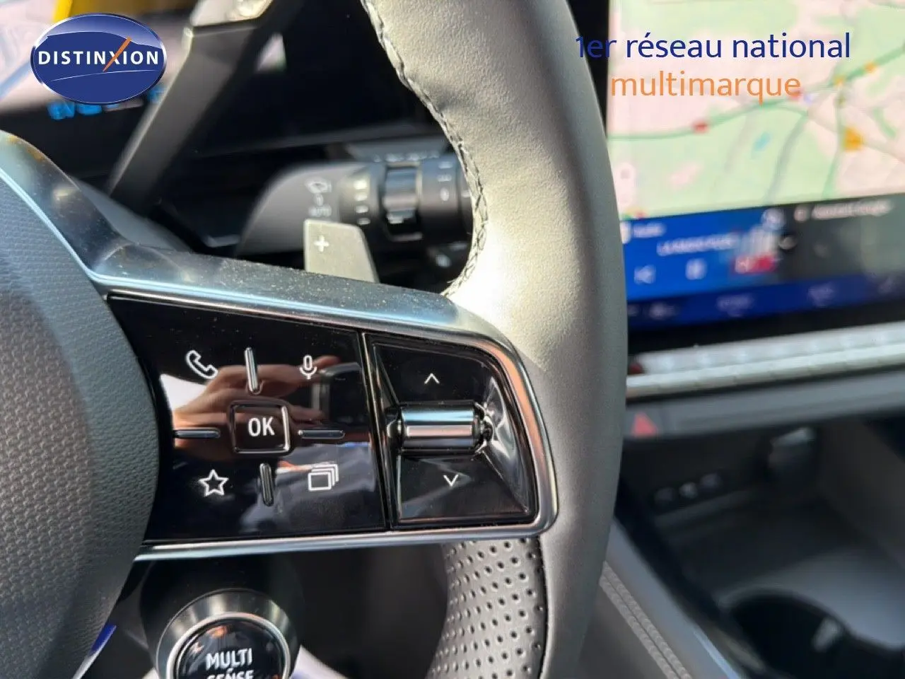 Gros plan sur les commandes gauche du volant du Renault Espace noir étoile métal, avec écran tactile flou en arrière-plan.