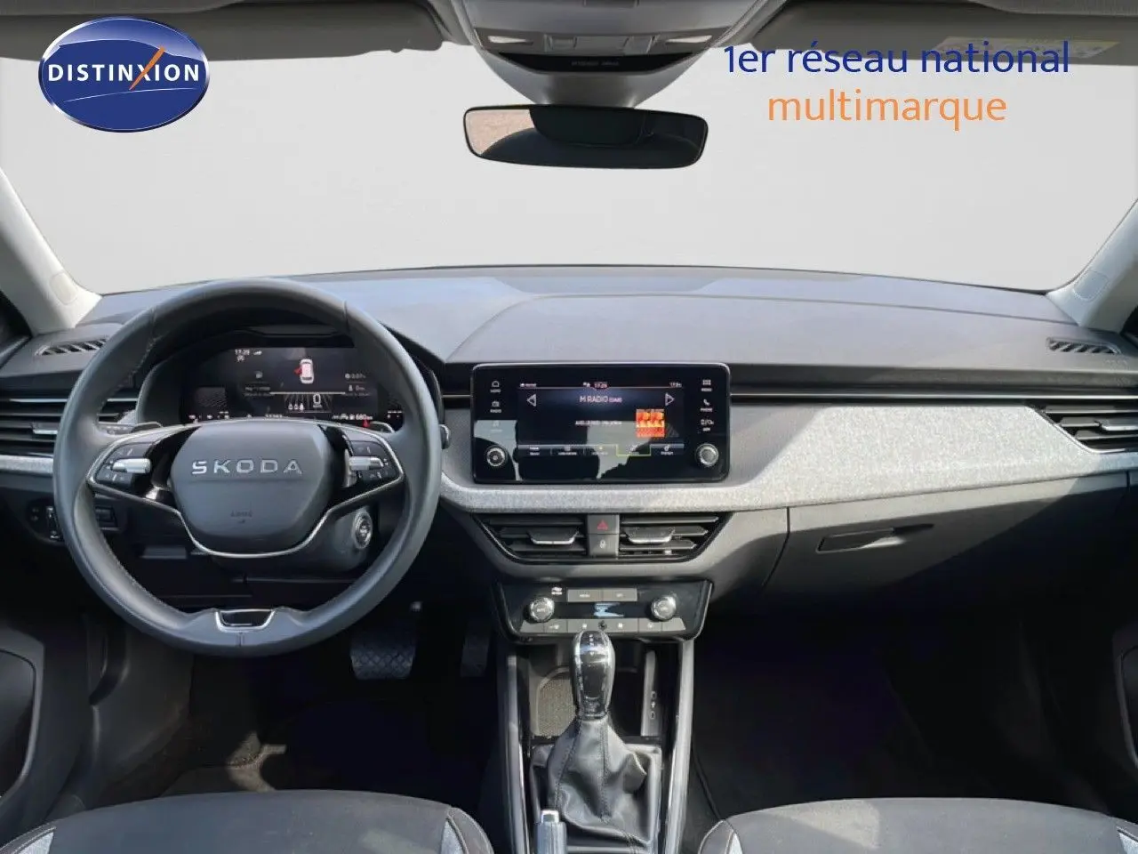 Vue intérieure frontale du tableau de bord du Skoda Kamiq gris argent, avec écran tactile central et volant multifonction.
