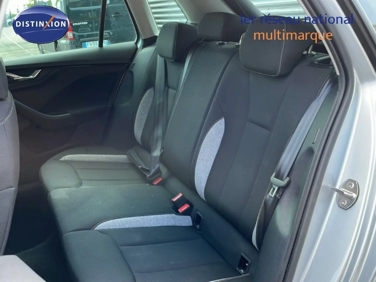 Vue intérieure côté arrière droit du Skoda Kamiq 2025 gris argent, montrant les sièges arrière en tissu noir et gris.