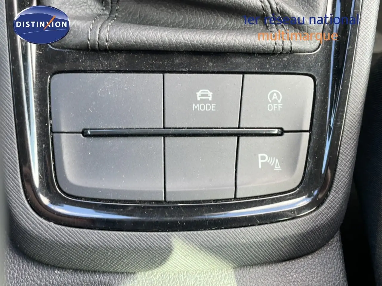 Gros plan sur les boutons de commande du mode de conduite et assistance au stationnement dans la console centrale d’un Skoda Kamiq gris argent.