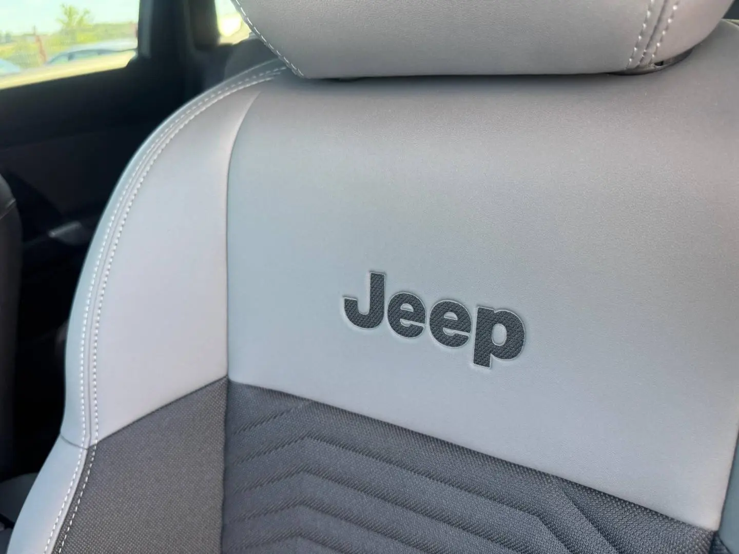 Gros plan sur le siège avant gris clair et noir avec logo Jeep brodé, intérieur du Jeep Compass 2026.