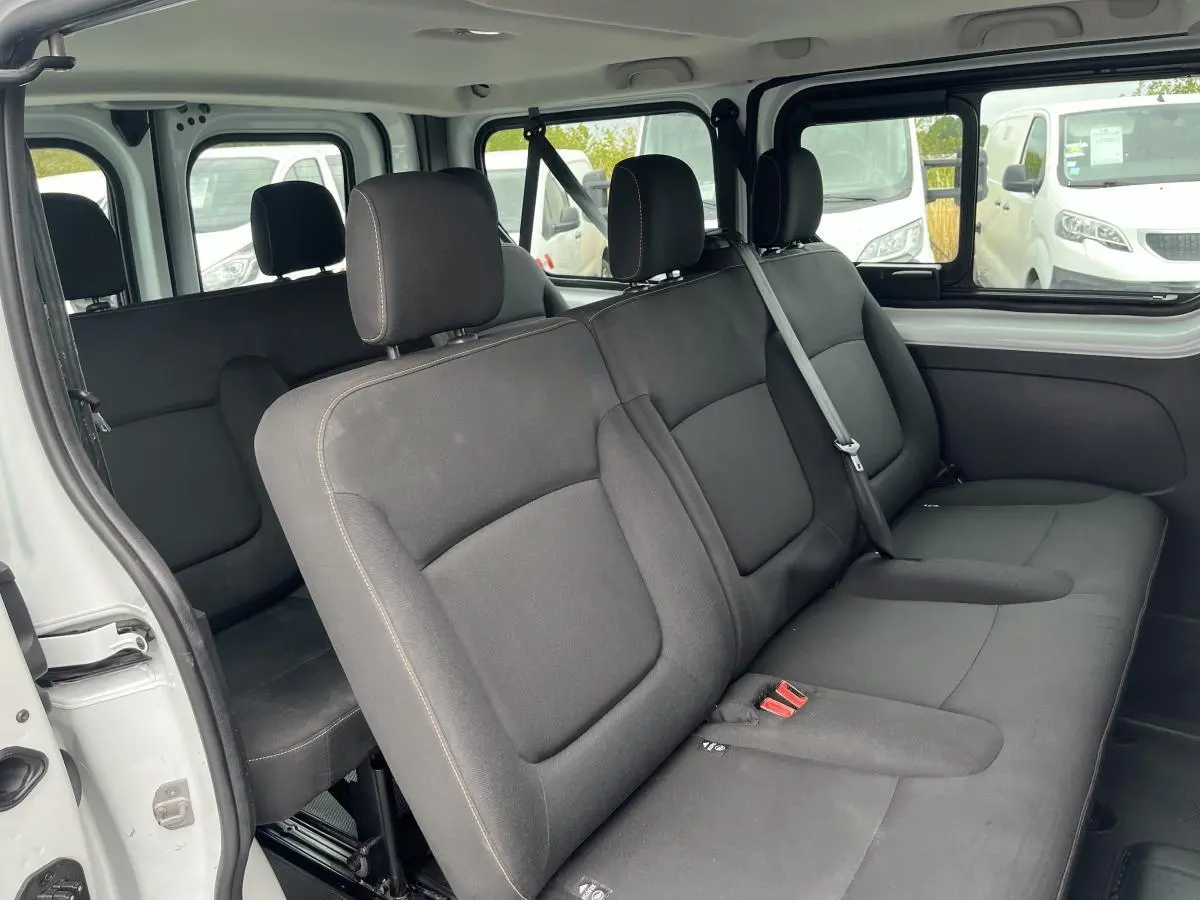Banquette arrière noire vue côté gauche dans un Renault Trafic Fourgon blanc avec porte coulissante ouverte.