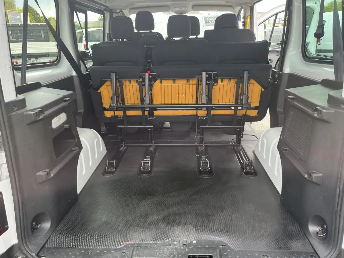 Vue arrière intérieure du Renault Trafic Fourgon blanc 2016 montrant la banquette arrière relevée et l'espace de chargement.