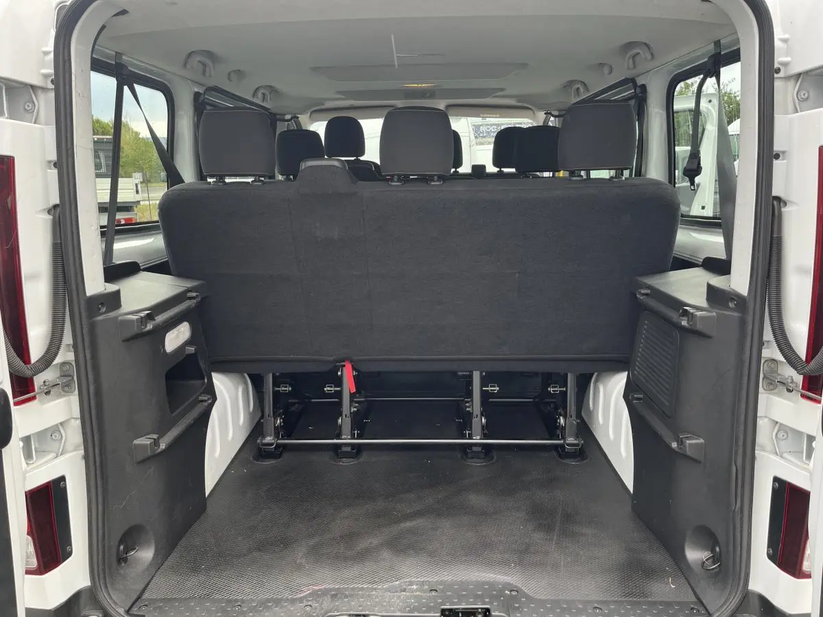 Vue arrière ouverte du Renault Trafic Fourgon blanc montrant la banquette arrière noire et l'espace de chargement vide.