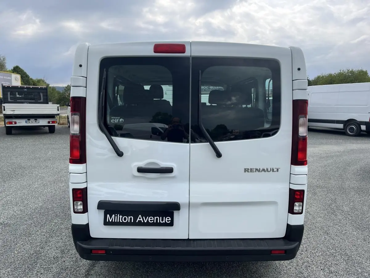 Vue arrière du Renault Trafic Fourgon blanc avec portes vitrées et essuie-glaces sur chaque vitre.