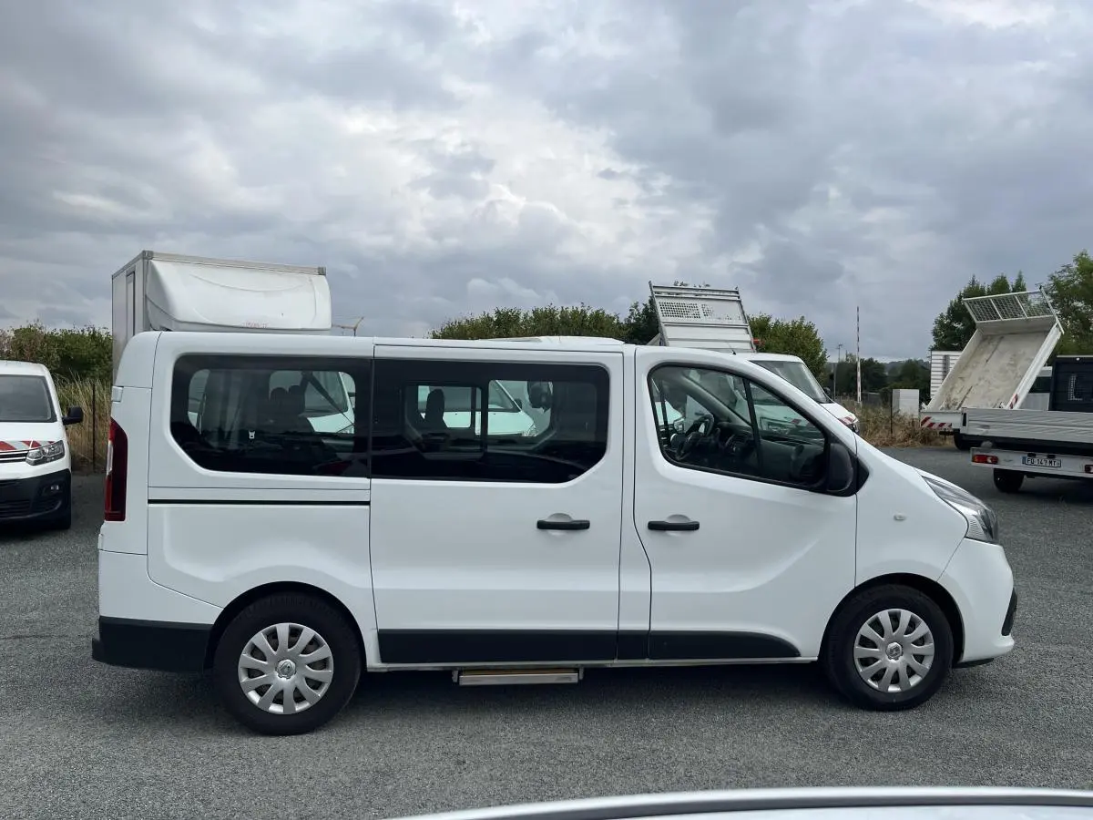 Profil côté gauche d'un Renault Trafic Fourgon blanc avec porte latérale coulissante vitrée et enjoliveurs 16 pouces.