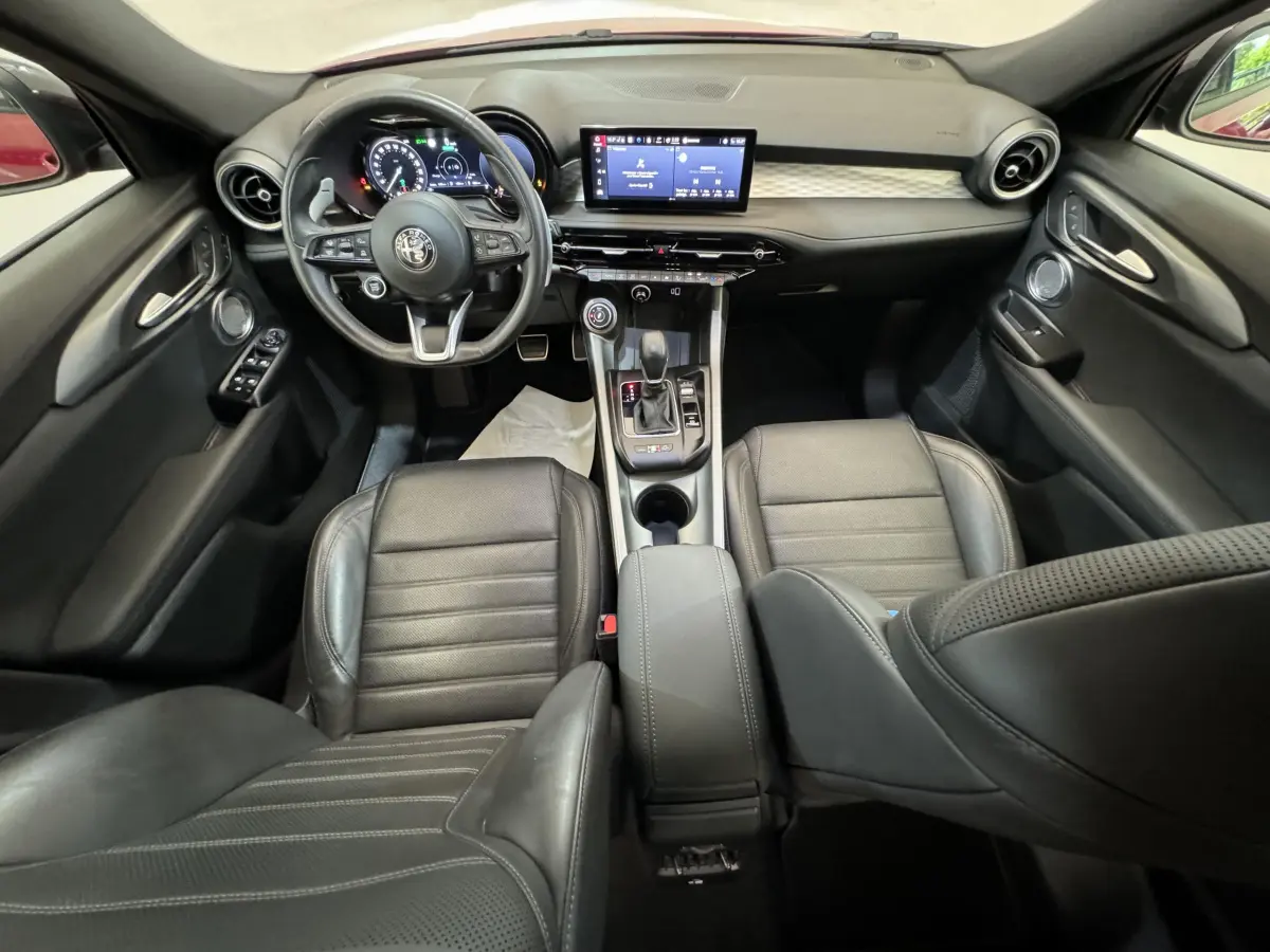 Intérieur noir de l'Alfa Romeo Tonale 2023, vue avant centrée sur tableau de bord et console centrale moderne.